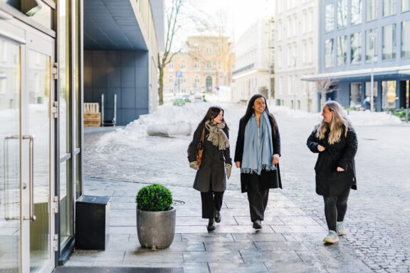 Tre kvinner går inn mot inngangsdøren på vei til jobb.